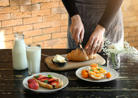 Woman preparing breakfast with growing at tableの写真素材