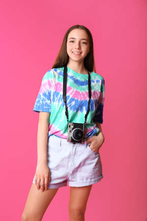 Teenage girl with photo camera on color background