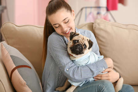 Teenage girl with cute pug dog at home
