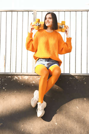 Stylish young woman with skateboard outdoorsの写真素材