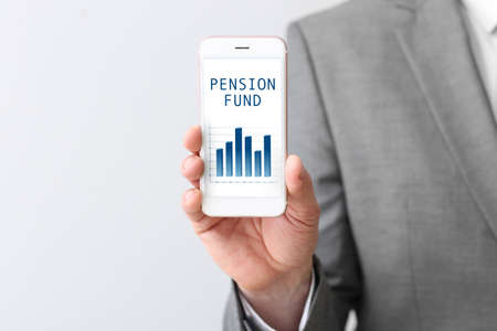 Businessman holding mobile phone with open page of online pension fund on light backgroundの写真素材