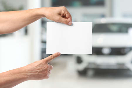 Male hands with blank poster in car showroom