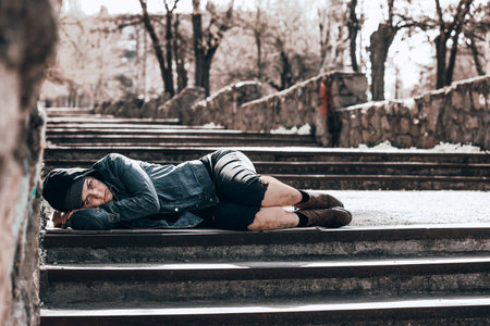 Poor homeless woman lying on stairs outdoorsの写真素材
