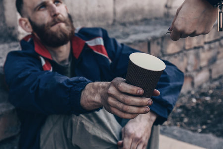 Woman giving money to poor homeless man outdoorsの写真素材