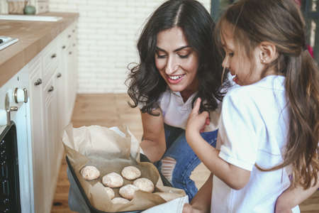 Happy mother with daughter preparing cookies in kitchen at homeの写真素材