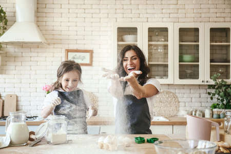 Happy mother with daughter preparing cookies in kitchen at home
