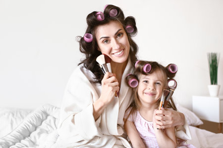 Mother with cute daughter doing makeup at homeの写真素材