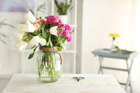 Vase with bouquet of flowers on tableの写真素材