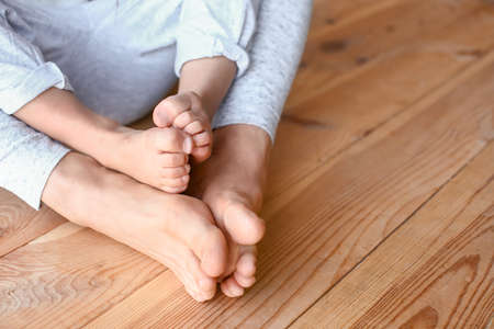 Legs of mother and her daughter on wooden backgroundの写真素材
