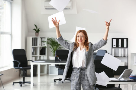Portrait of stressed mature businesswoman throwing papers in officeの写真素材