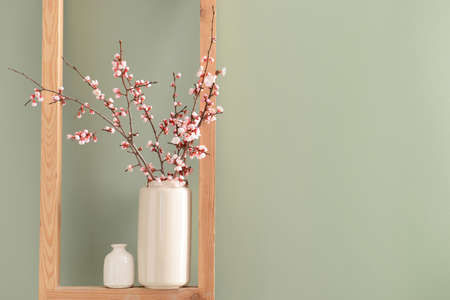 Vase with beautiful blossoming branches on shelfの写真素材