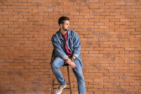 Fashionable young man near brick wall