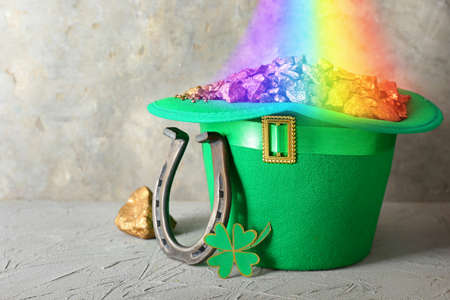 Hat with leprechaun's treasure, horseshoe and clover for St. Patrick's Day on gray background