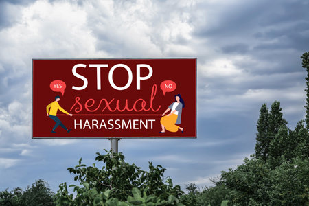 Advertising billboard with text STOP SEXUAL HARASSMENT on city streetの写真素材