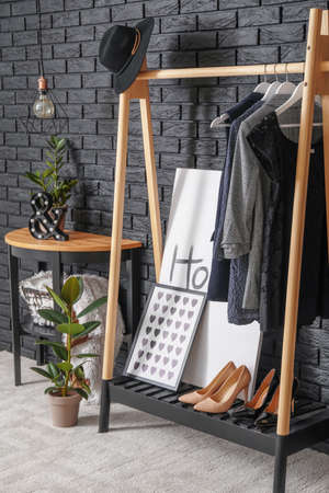 Rack with clothes near dark brick wall in hallの写真素材