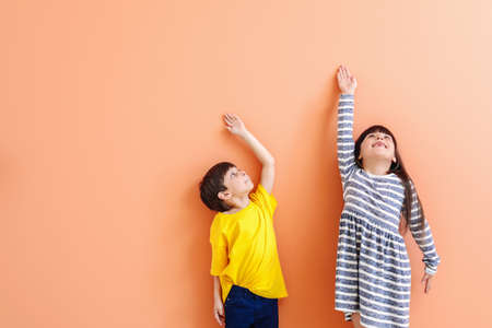 Cute little children measuring height near color wallの写真素材