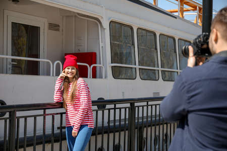 Photographer taking picture of beautiful woman on embankment