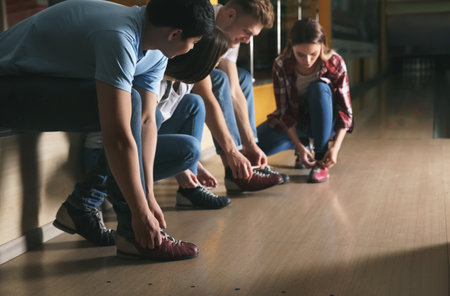 Friends changing shoes before playing bowling in clubの写真素材
