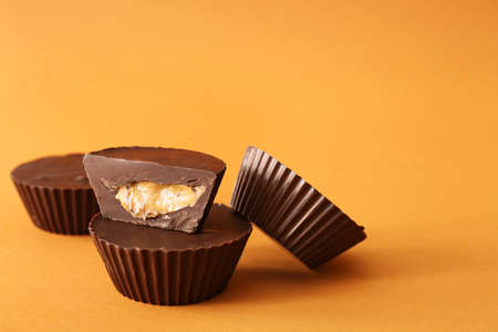 Tasty chocolate peanut butter cups on color backgroundの写真素材
