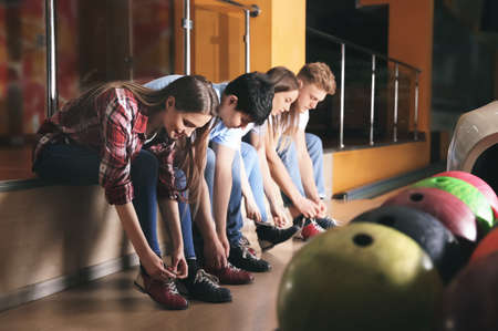 Friends changing shoes before playing bowling in clubの写真素材