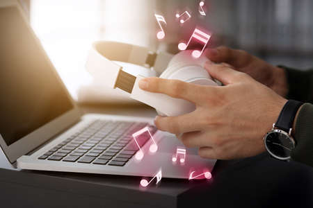 Man with headphones and laptop listening to music in office