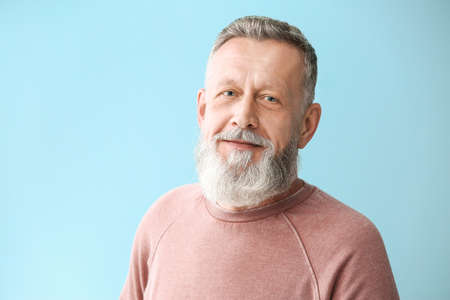 Portrait of handsome senior man on color background