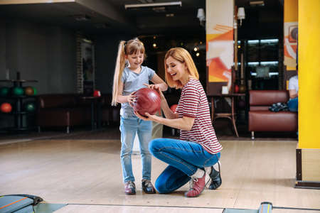 Woman and her little daughter playing bowling in clubの写真素材