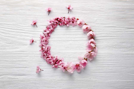 Frame made of beautiful flowers on white wooden background