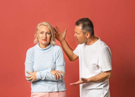 Quarrelling middle-aged couple on color background