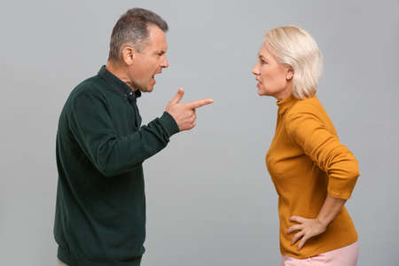 Quarrelling middle-aged couple on gray background