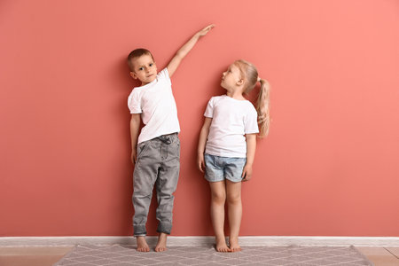 Little children measuring height near wallの写真素材
