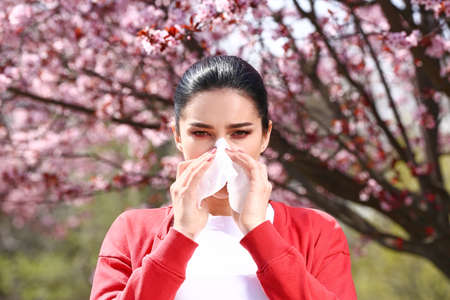 Young woman with nose wiper near blooming treeの写真素材