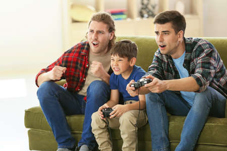 Gay couple with adopted child playing video game at home