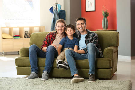 Happy gay couple with adopted child at homeの写真素材