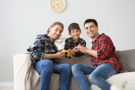 Happy gay couple playing with adopted child at homeの写真素材