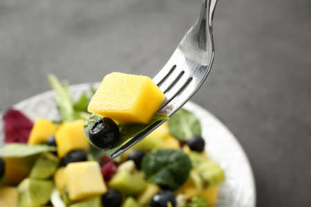 Eating of tasty mango salad, closeup