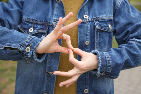 Young deaf mute woman using sign language outdoors