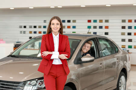 Saleswoman with buyer in modern car showroom