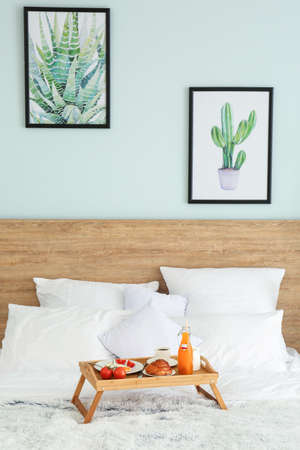 Table with tasty breakfast on bed