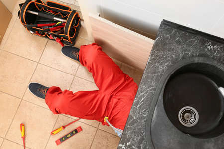 Plumber repairing sink in kitchen