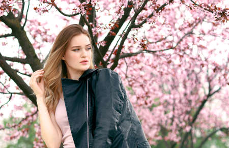 Beautiful young woman near blossoming tree on spring dayの写真素材