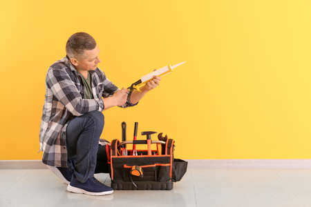 Handsome plumber with tools near color wallの写真素材