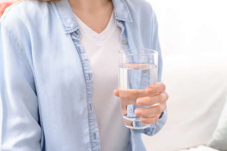Woman with glass of fresh water at home, closeup