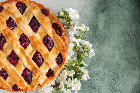 Tasty cherry pie and flowers on table