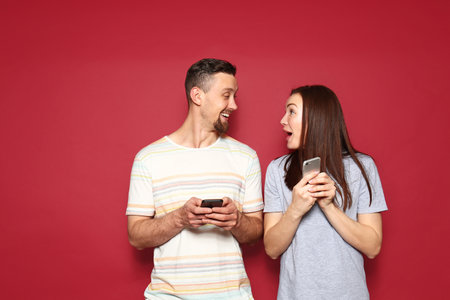 Young couple with mobile phones on color backgroundの写真素材