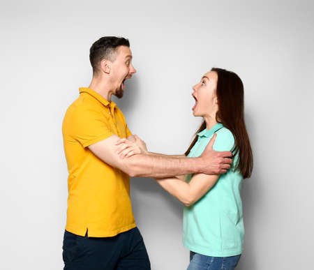Excited young couple on light background