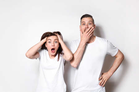 Shocked young couple on light backgroundの写真素材