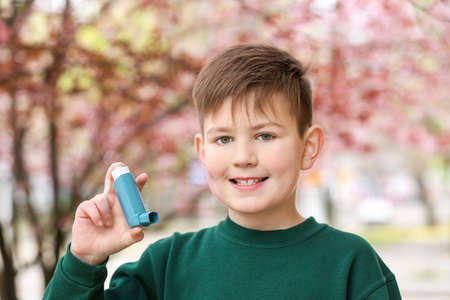 Boy with inhaler outdoors on spring day
