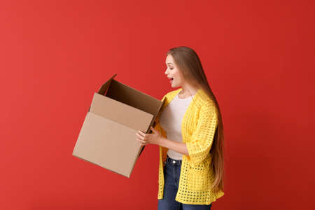 Surprised woman with open cardboard box on color backgroundの写真素材