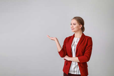 Portrait of businesswoman showing something on light backgroundの写真素材